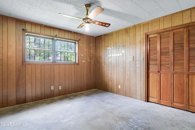 506 Rice Ln, Opelousas, LA 70570 - unfurnished bedroom with concrete flooring, wood walls, a closet, and ceiling fan