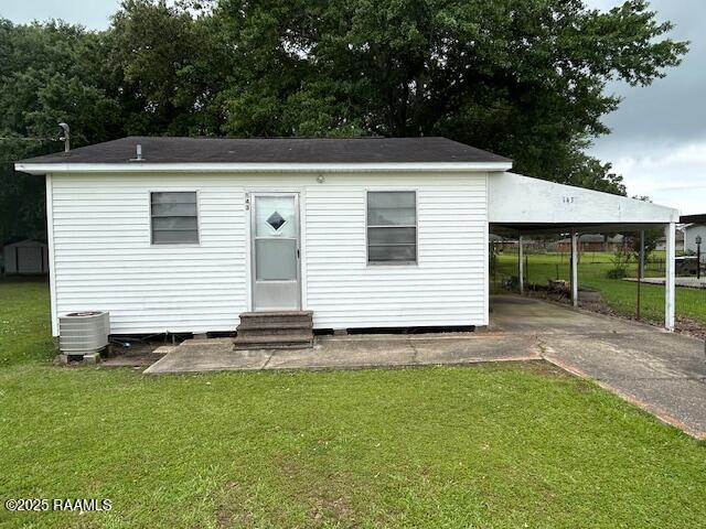 143 Monette St, Ville Platte, LA 70586 - view of front of property with entry steps, an attached carport, concrete driveway, a front yard, and central AC