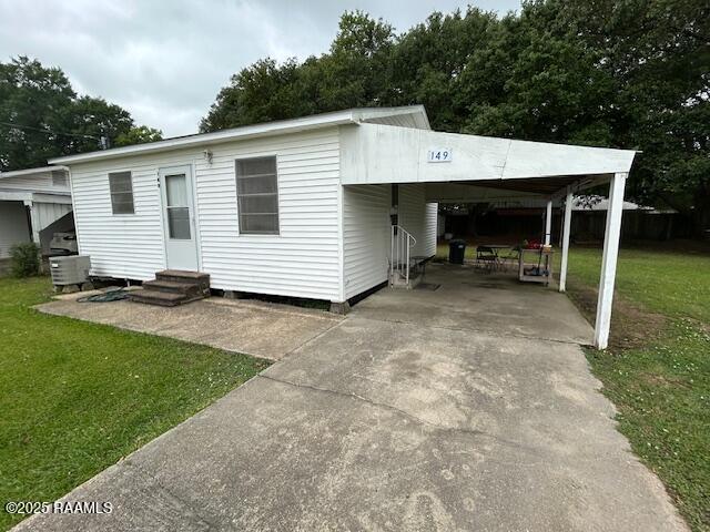 143 Monette St, Ville Platte, LA 70586 - manufactured / mobile home with entry steps, concrete driveway, a front lawn, and an attached carport