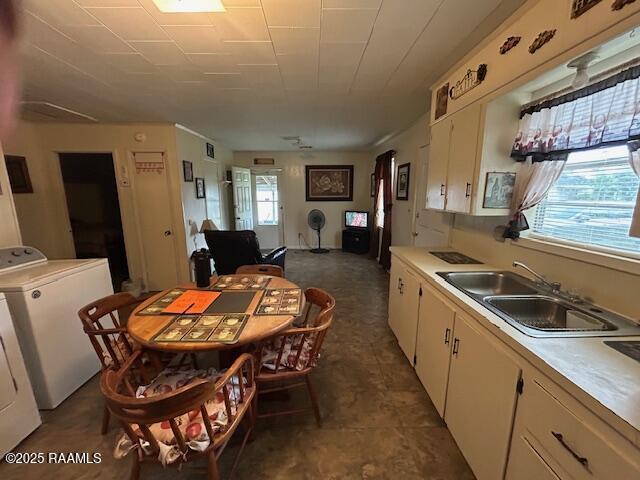 143 Monette St, Ville Platte, LA 70586 - kitchen featuring washer / dryer, a sink, light countertops, and white cabinetry