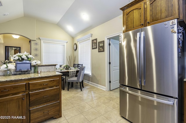 100 Mirada Ln, Lafayette, LA 70508 - kitchen with freestanding refrigerator, lofted ceiling, arched walkways, light tile patterned floors, and light stone counters