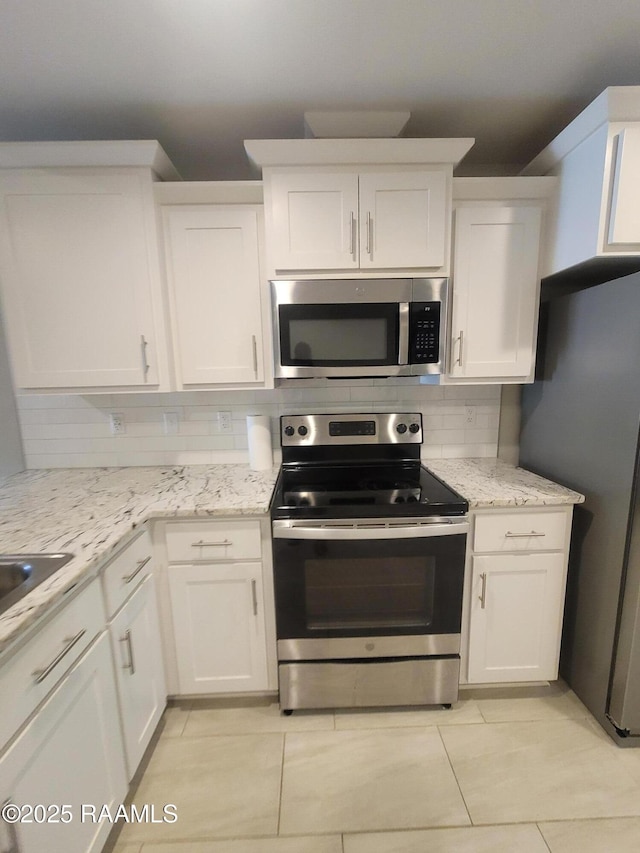 313 Harvest Ln, Abbeville, LA 70510 - kitchen featuring stainless steel appliances, decorative backsplash, white cabinetry, light tile patterned flooring, and light stone counters