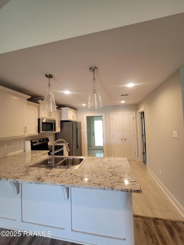 313 Harvest Ln, Abbeville, LA 70510 - kitchen with stainless steel appliances, a peninsula, white cabinetry, a kitchen bar, and recessed lighting