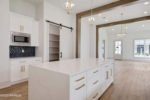 104 Wishing Well Dr, Broussard, LA 70518 - kitchen featuring stainless steel microwave, a barn door, beam ceiling, light wood-type flooring, and decorative backsplash