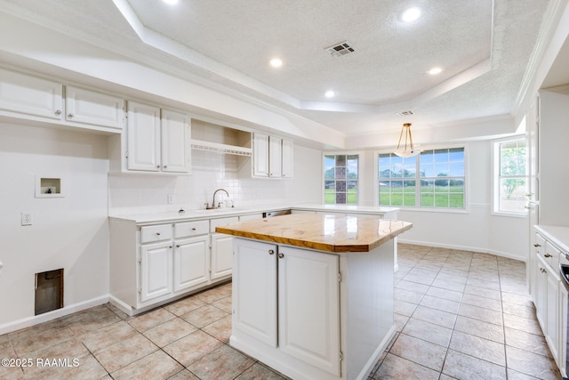 421 Plantation Rd, Opelousas, LA 70570 - kitchen featuring a raised ceiling, white cabinetry, a kitchen island, backsplash, and a textured ceiling