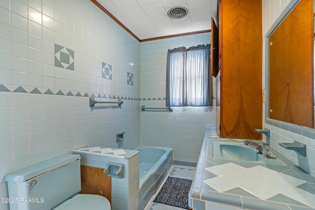 423 E 1st St, Jennings, LA 70546 - bathroom featuring tile walls, toilet, a tub to relax in, and double vanity