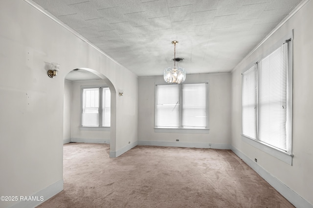 423 E 1st St, Jennings, LA 70546 - carpeted empty room featuring ornamental molding, arched walkways, a chandelier, and baseboards