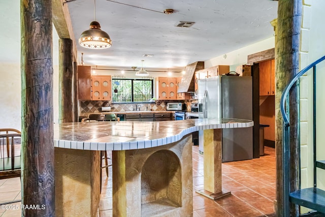 146 Steiner Rd, Lafayette, LA 70508 - kitchen featuring appliances with stainless steel finishes, tile countertops, brown cabinets, light tile patterned flooring, and tasteful backsplash