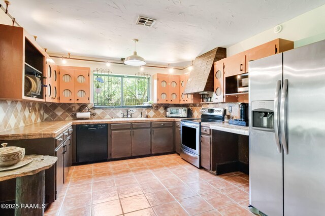 146 Steiner Rd, Lafayette, LA 70508 - kitchen featuring stainless steel appliances, tile countertops, wall chimney range hood, and light tile patterned flooring