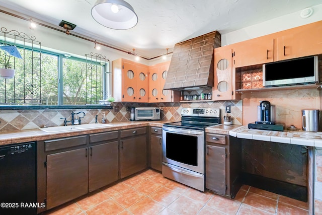 146 Steiner Rd, Lafayette, LA 70508 - kitchen featuring appliances with stainless steel finishes, a sink, wall chimney exhaust hood, and tile countertops