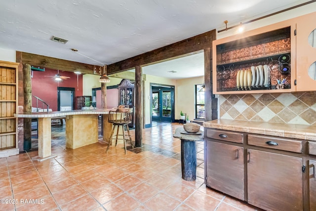 146 Steiner Rd, Lafayette, LA 70508 - kitchen with tasteful backsplash, light tile patterned flooring, ceiling fan, a kitchen bar, and open floor plan