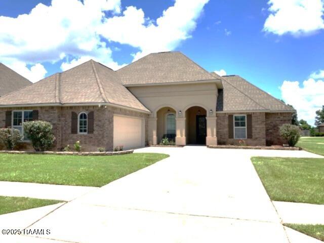 123 Angel Rock Ln, Broussard, LA 70518 - view of front of property featuring an attached garage, a front lawn, concrete driveway, and brick siding