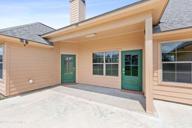 1117 Jules Broussard Rd, Breaux Bridge, LA 70517 - entrance to property featuring a patio area, a shingled roof, and a chimney