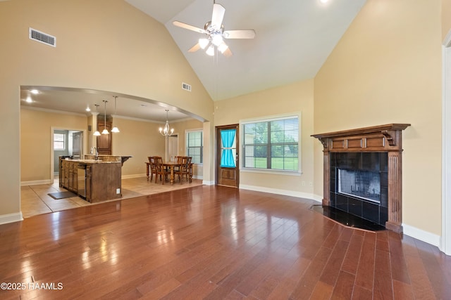 1117 Jules Broussard Rd, Breaux Bridge, LA 70517 - unfurnished living room with arched walkways, wood finished floors, a tiled fireplace, high vaulted ceiling, and a sink