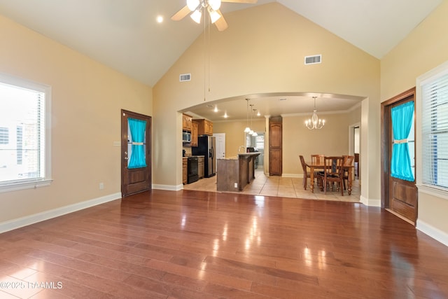 1117 Jules Broussard Rd, Breaux Bridge, LA 70517 - unfurnished living room featuring arched walkways, high vaulted ceiling, a ceiling fan, light wood-style flooring, and a chandelier