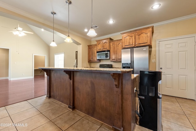 1117 Jules Broussard Rd, Breaux Bridge, LA 70517 - kitchen with stainless steel appliances, light tile patterned floors, a kitchen bar, ceiling fan, and brown cabinets