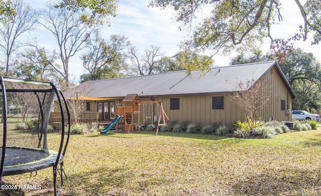 115 Hiawatha Rd, Lafayette, LA 70501 - back of house with a trampoline, a playground, a lawn, metal roof, and board and batten siding