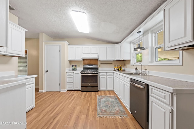 4802 Lafitte St, New Iberia, LA 70560 - kitchen featuring appliances with stainless steel finishes, a sink, custom exhaust hood, light wood finished floors, and white cabinetry