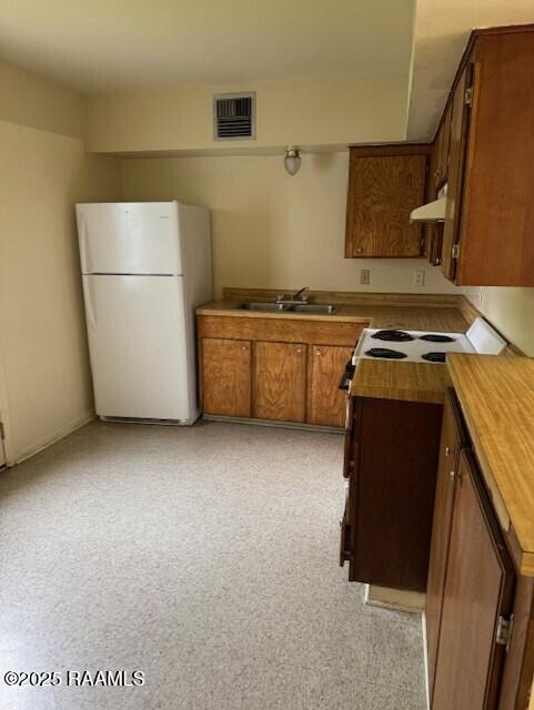 1500 Norman Bauer Dr, Franklin, LA 70538 - kitchen with freestanding refrigerator, exhaust hood, brown cabinets, a sink, and wood counters