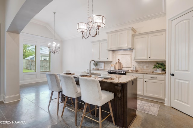 203 Sanctuary Ln, Lafayette, LA 70503 - kitchen featuring a chandelier, tasteful backsplash, range, a center island with sink, and light stone counters