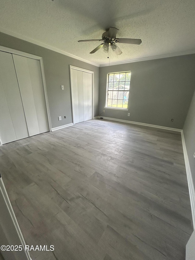 106 Dove Cir, Lafayette, LA 70508 - unfurnished bedroom with multiple closets, a textured ceiling, wood finished floors, ornamental molding, and baseboards