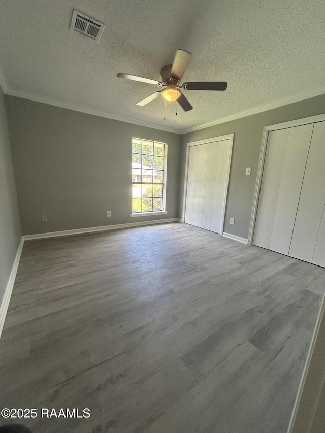 106 Dove Cir, Lafayette, LA 70508 - unfurnished bedroom with crown molding, multiple closets, a textured ceiling, wood finished floors, and baseboards