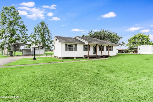 231 La Compagne St, Opelousas, LA 70570 - view of front facade with a carport, a front lawn, concrete driveway, a shingled roof, and an outbuilding