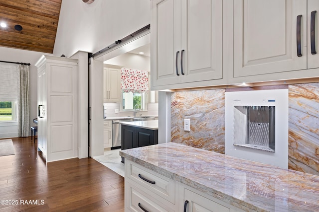 235 N Fieldspan Rd, Scott, LA 70583 - kitchen with stainless steel dishwasher, dark wood-style floors, vaulted ceiling, light stone counters, and a barn door