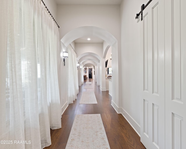 235 N Fieldspan Rd, Scott, LA 70583 - corridor featuring arched walkways, dark wood finished floors, baseboards, and a barn door