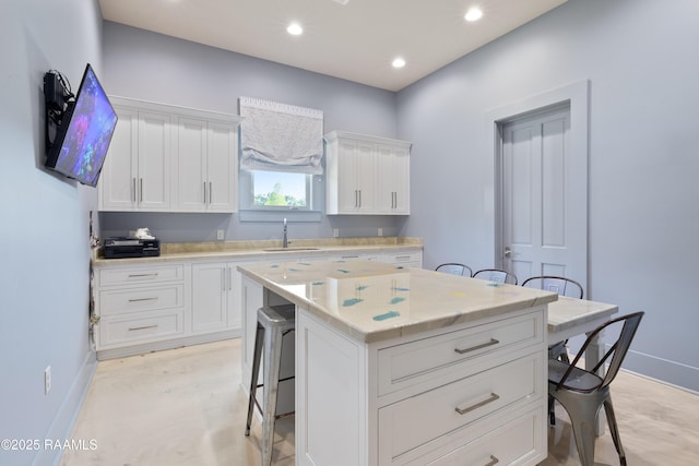 235 N Fieldspan Rd, Scott, LA 70583 - kitchen featuring a sink, a breakfast bar area, baseboards, white cabinets, and a kitchen island