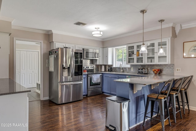 421 Karen Dr, Lafayette, LA 70503 - kitchen featuring appliances with stainless steel finishes, a peninsula, dark wood-type flooring, decorative backsplash, and crown molding