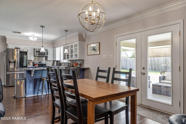 421 Karen Dr, Lafayette, LA 70503 - dining room with french doors, a chandelier, dark wood-style flooring, and ornamental molding