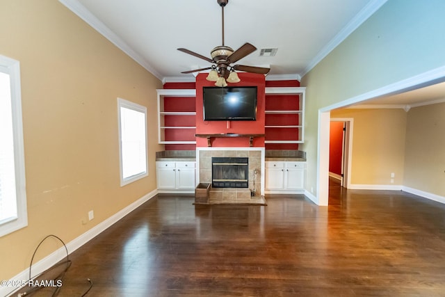 306 Oak St, Iota, LA 70543 - unfurnished living room featuring a tiled fireplace, crown molding, ceiling fan, dark wood-style flooring, and baseboards