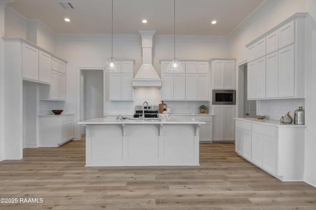 203 Redfern St, Lafayette, LA 70508 - kitchen with stainless steel microwave, tasteful backsplash, an island with sink, light wood-type flooring, and ornamental molding