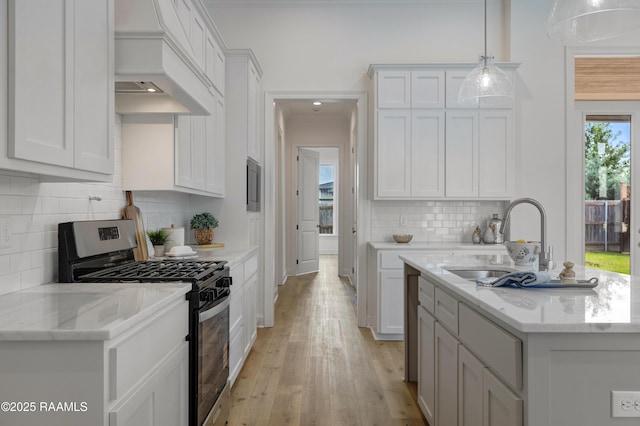 203 Redfern St, Lafayette, LA 70508 - kitchen featuring gas range, custom range hood, light wood-style flooring, backsplash, and white cabinetry