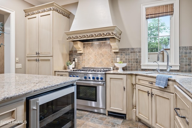 104 Avallach Dr, Lafayette, LA 70503 - kitchen featuring stainless steel range, custom range hood, wine cooler, decorative backsplash, and cream cabinets