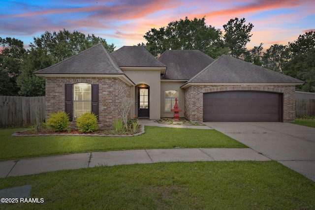 103 Swallows Pass, Carencro, LA 70520 - french provincial home featuring brick siding, an attached garage, driveway, roof with shingles, and stucco siding