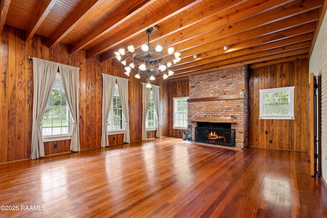 1414 E Bayou Pkwy, Lafayette, LA 70508 - unfurnished living room with wood finished floors, a chandelier, wooden walls, a fireplace, and wood ceiling with exposed beams