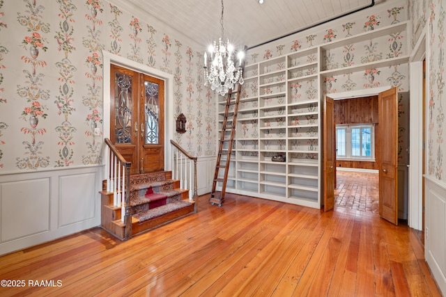 1414 E Bayou Pkwy, Lafayette, LA 70508 - staircase featuring wallpapered walls, wainscoting, a chandelier, hardwood / wood-style floors, and a decorative wall