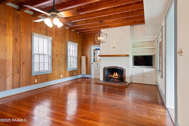1414 E Bayou Pkwy, Lafayette, LA 70508 - unfurnished living room featuring hardwood / wood-style flooring, a ceiling fan, a fireplace, wood ceiling with exposed beams, and wood walls