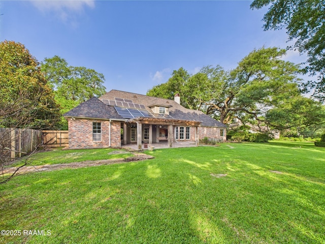 105 Oak Aly, Lafayette, LA 70508 - rear view of house with a patio, roof mounted solar panels, a chimney, and brick siding