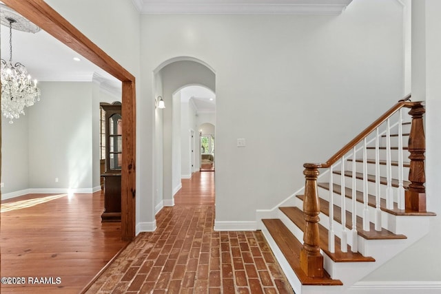 105 Oak Aly, Lafayette, LA 70508 - hallway featuring arched walkways, baseboards, crown molding, a chandelier, and stairs