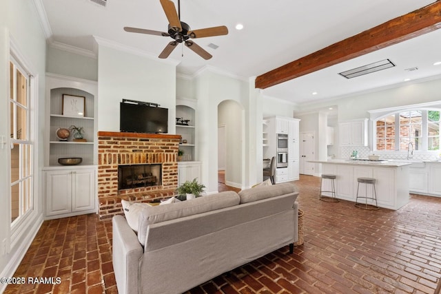 105 Oak Aly, Lafayette, LA 70508 - living area featuring brick flooring, a brick fireplace, ceiling fan, ornamental molding, and recessed lighting