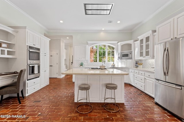 105 Oak Aly, Lafayette, LA 70508 - kitchen with stainless steel appliances, brick flooring, white cabinets, a kitchen breakfast bar, and recessed lighting