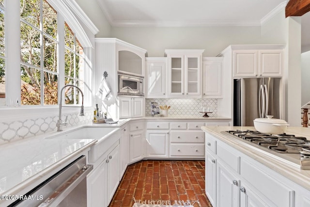 105 Oak Aly, Lafayette, LA 70508 - kitchen featuring appliances with stainless steel finishes, brick floors, light countertops, backsplash, and crown molding