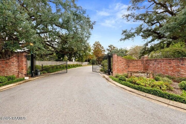 105 Oak Aly, Lafayette, LA 70508 - view of asphalt road with a gate, a gated entry, and curbs