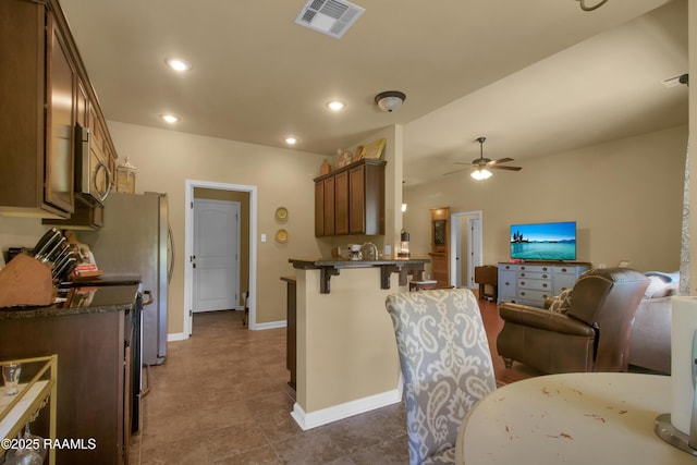 205 Broland Dr, Duson, LA 70529 - kitchen featuring open floor plan, a kitchen breakfast bar, stainless steel microwave, a peninsula, and ceiling fan