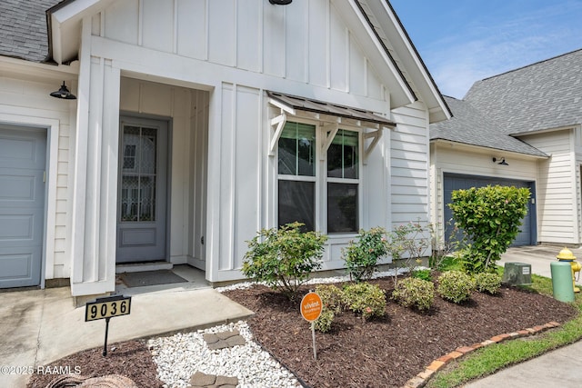 9036 Stonecroft Ave, Baton Rouge, LA 70810 - view of exterior entry with board and batten siding, roof with shingles, and an attached garage