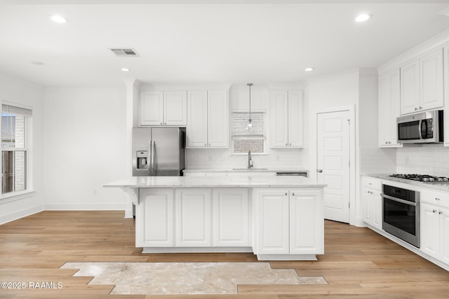 9036 Stonecroft Ave, Baton Rouge, LA 70810 - kitchen with appliances with stainless steel finishes, a sink, decorative backsplash, a kitchen island, and white cabinetry