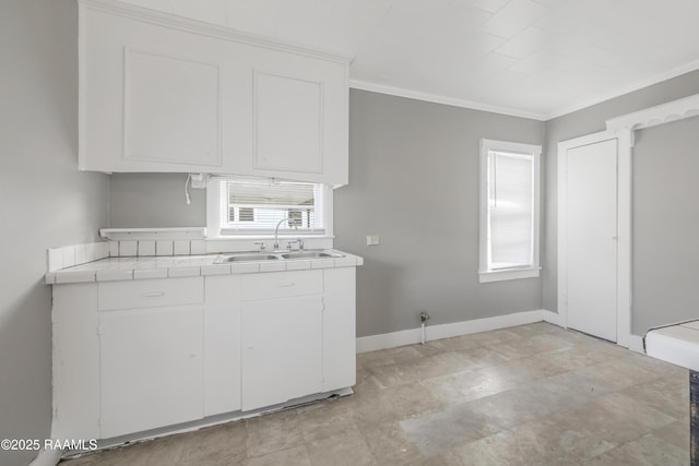 1323 Tarleton, Jeanerette, LA 70544 - kitchen with tile counters, a sink, white cabinets, ornamental molding, and plenty of natural light